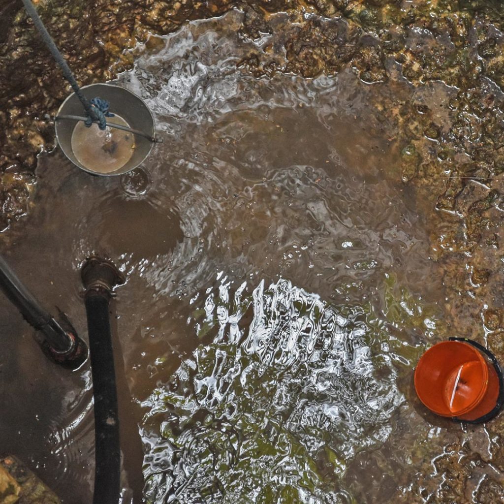 Water at the bottom of a water well with a bucket.
